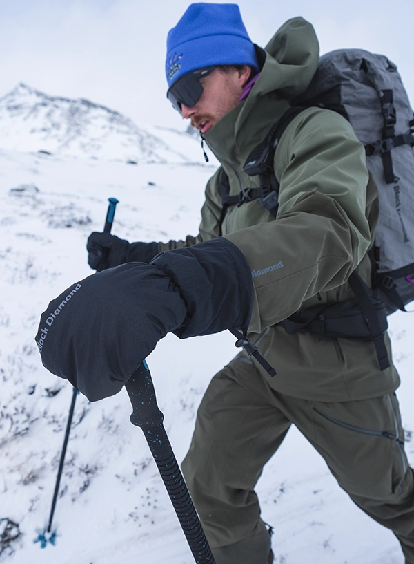 Jak vybrat lyžařské rukavice? Lyžař v tlustých palčácích při výstupu.