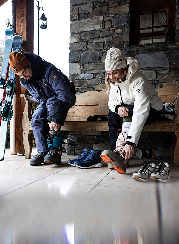 Lyžaři si obouvají lyžařské boty.