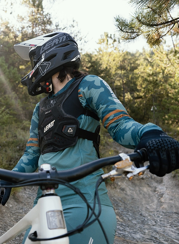 Enduro cyklista v helmě, chrániči trupu a cyklistických rukavicích na kole.